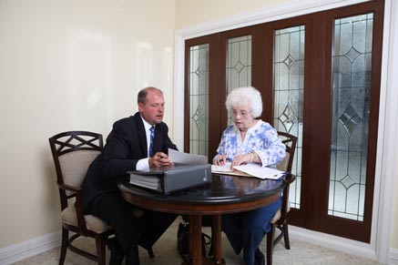 Man in business suit meeting with a woman at a table looking at documents.